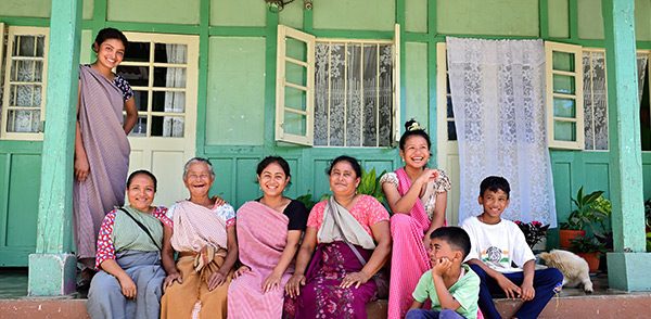 community A group of smiling community members sitting in front of a home