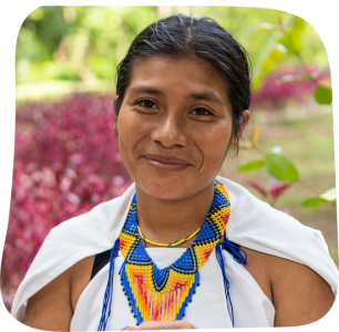 A woman in traditional Indigenous clothing and beaded jewelry smiles outdoors, representing cultural identity and community strength. © CIVIC