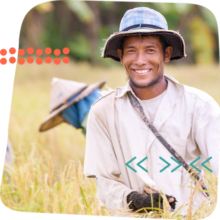 farmer A smiling farmer in a wide-brimmed hat stands in a rice field, symbolizing sustainable agriculture and rural livelihoods. © CIVIC